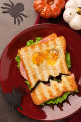 Cute monster sandwich with fried eggs on grey textured table, flat lay. Halloween snack