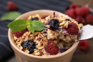 Eating tasty baked oatmeal with berries at table, closeup
