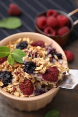 Eating tasty baked oatmeal with berries at table, closeup