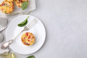 Freshly baked bacon and egg muffins with cheese served on light gray table, flat lay. Space for text