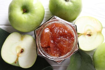 Glass jar of delicious apple jam and fresh fruits on white wooden table, flat lay