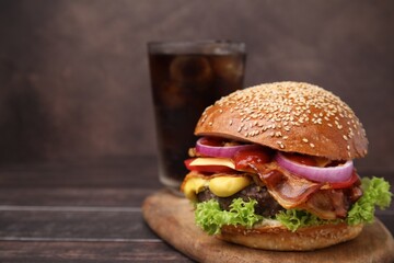 Delicious burger with bacon, patty and vegetables on wooden table, closeup. Space for text
