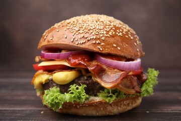 Delicious burger with bacon, patty and vegetables on wooden table, closeup