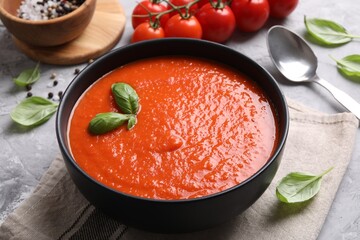 Delicious tomato cream soup served on grey textured table, closeup