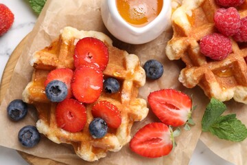 Delicious Belgian waffles with fresh berries and honey on table, top view