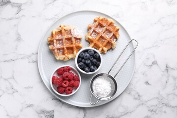 Delicious Belgian waffles with fresh berries and powdered sugar on white marble table, top view