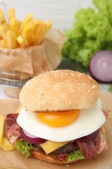 Delicious burger with fried egg on table, closeup. Space for text