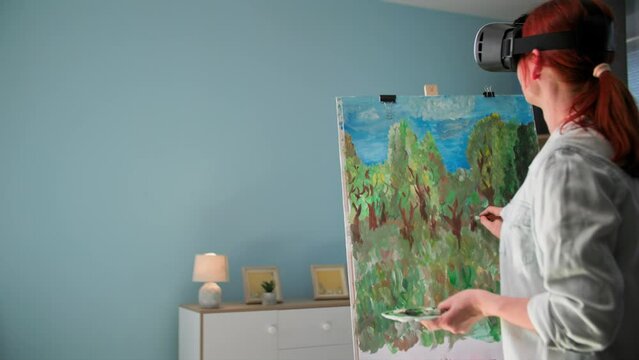 creative young woman uses modern technology and draws a picture with brushes and paints in vair glasses while standing in room