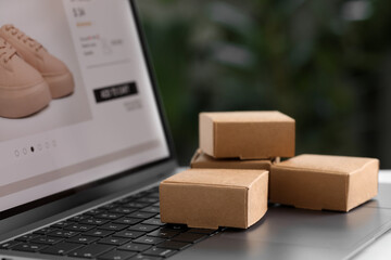 Online store. Small parcels on laptop, closeup. Space for text