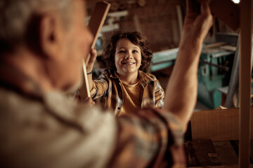 Senior male carpenter showing his grandson a wood frame in a carpentry shop