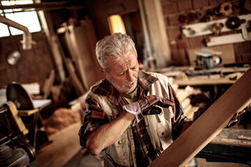 Senior male carpenter measuring wood in a carpentry shop