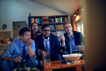 Young businessmen watching sports on the tv after work in the living room