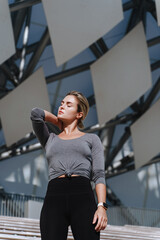 Confident woman athlete wearing female sportswear posing against modern futuristic background