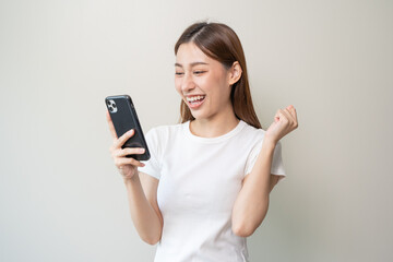 Fototapeta premium Happy Asian woman holding a smartphone and winning the prize.