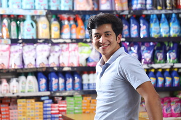 Beautiful portrait of handsome and smiling Indian young man shopping and posing in hypermarket....