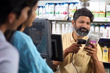 Bearded guy on the billing counter scanning the products. Customers standing in the queue in a mini...