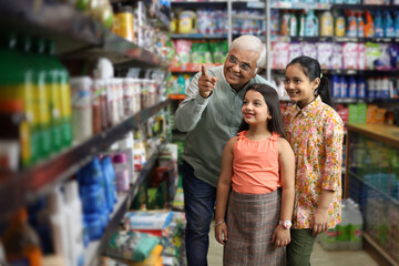 Happy Grandfather and Grand Daughters enjoying purchasing in grocery store. Buying grocery for home in supermarket. Grand daughters are happy with grandpa