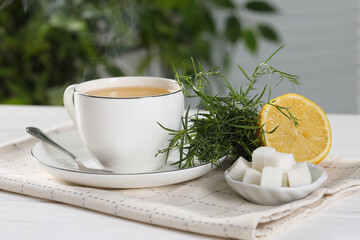 Aromatic herbal tea, fresh tarragon sprigs, sugar cubes and lemon on white wooden table, closeup