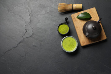 Obraz na płótnie Canvas Cup of fresh matcha tea, bamboo whisk, teapot and green powder on black textured table, flat lay. Space for text