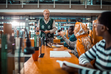 Middle aged librarian helping students in the college library