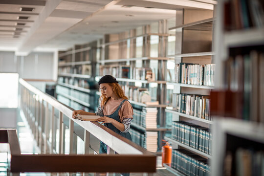 Wide angle view of a young female student reading at the university library