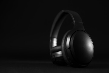 Fototapeta na wymiar Modern wireless headphones on black background, space for text