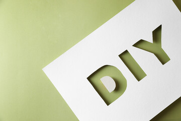 Stencil with abbreviation DIY on olive background, top view. Space for text