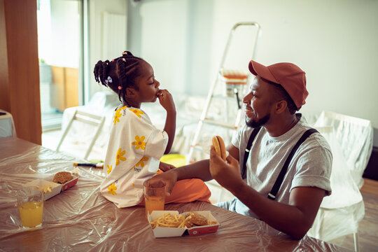 Young father and daughter having a lunch break from painting the living room at home