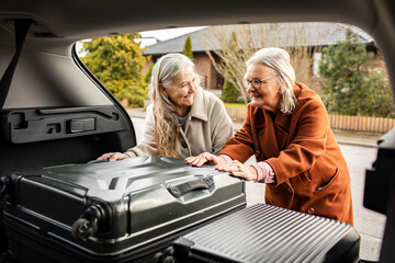 Senior lesbian couple packing their suitcases in the car for a holiday road trip