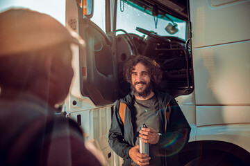Young truck driver entering the truck with his colleague and going on the road
