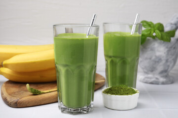 Glasses of tasty matcha smoothie and powder on white table