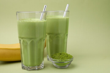 Glasses of tasty matcha smoothie and powder on pale green background. Space for text