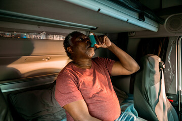 Senior truck driver using his inhaler on a break from driving in the truck