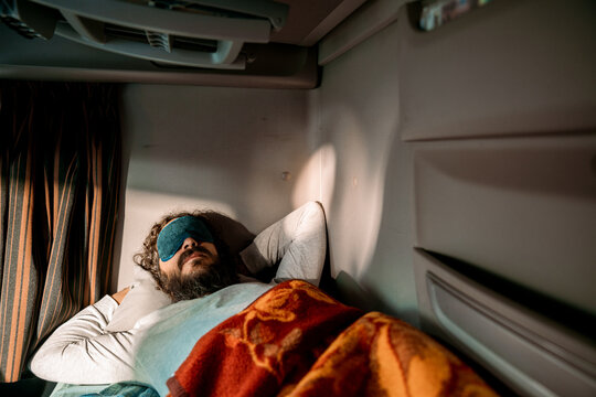Young truck driver sleeping in his cabin after working long routes overtime