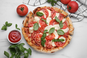 Delicious Caprese pizza with tomatoes, mozzarella and basil served on white marble table, flat lay