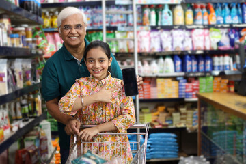 Happy Grandpa and Granddaughter enjoying purchasing in a grocery store. Buying grocery for home in a supermarket.