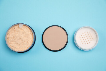 Three different face powders on light blue background, flat lay