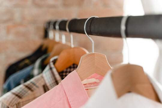 Clothing rack with variety of male shirts all hanging neatly on wooden hangers