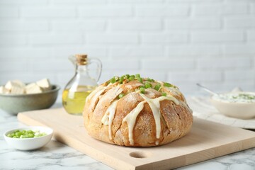 Freshly baked bread with tofu cheese and green onion on white marble table