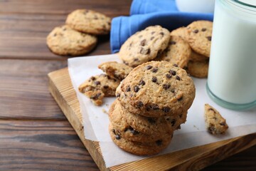 Delicious chocolate chip cookies and glass of milk on wooden table, space for text