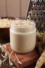 Spicy horseradish sauce in jar on wooden table, closeup