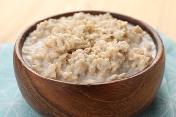 Tasty boiled oatmeal in bowl on table, closeup