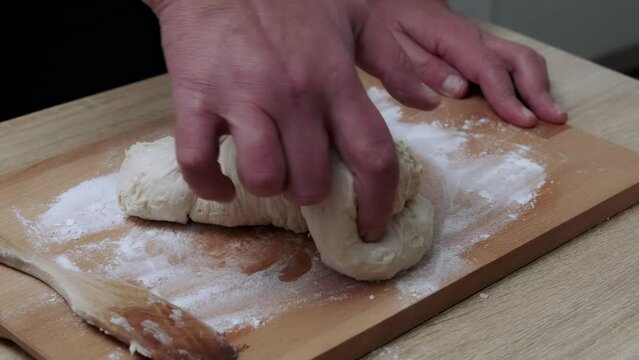 A home cook kneads the dough with his hands to bake delicious homemade bread.