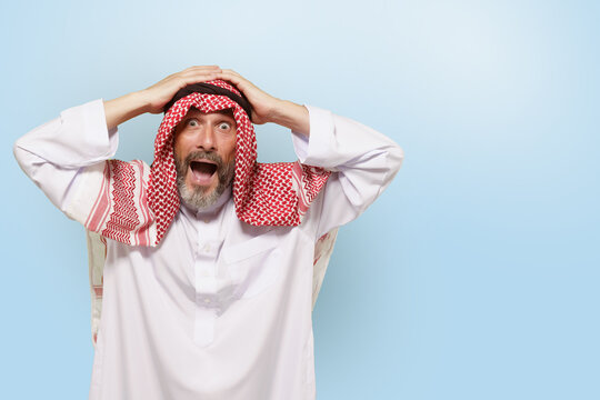 Excited Middle Eastern Arabian man, or Muslim, in traditional attire keffiyeh headscarf, with smile holds head. Joy and pride of Islamic people, cultural diversity and rich traditions of ethnic group.
