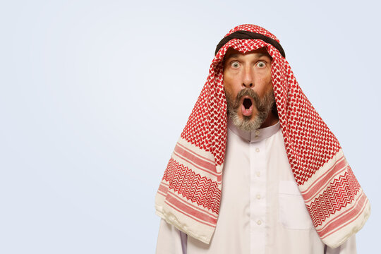 Arabian man, in keffiyeh, displays expression with shock, surprise and frustration, reflected by opened mouth. He isolated on gentle light blue background, illustrating cultural identity of ethnic
