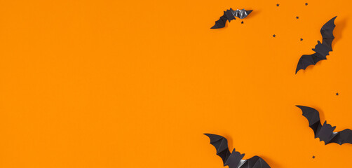 Halloween holiday with party decorations, black paper bats on orange background. Halloween concept. Flat lay, top view, copy space