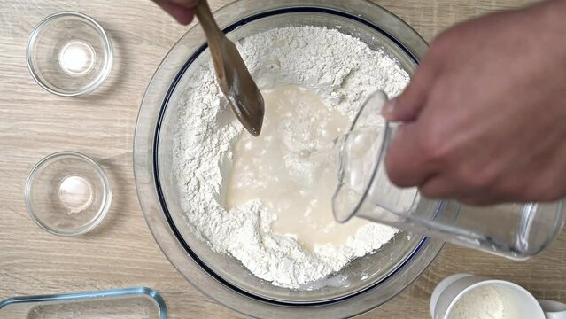 A man mixes salt and flour with his hands to prepare the dough for delicious homemade bread.