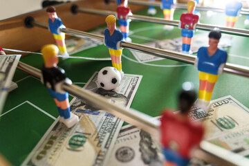Table football game with US dollar bills scattered around it, alluding to a betting concept
