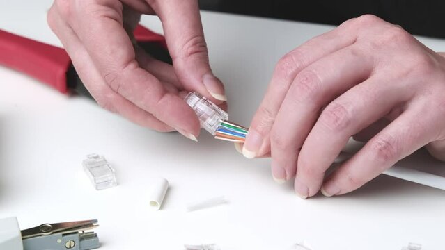 An engineer installs a new connector on a cable using a tool. Tool for crimping internet cable, cable and connectors on the desktop.