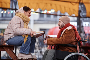 Side view portrait of young couple sharing hot drink while enjoying date in winter outdoors